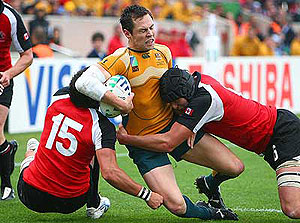 Australia's Julian Huxley is tackled by Canada's Dth van der Merwe, left, and Colin Yukes, right, during the Rugby World Cup Group B match between Australia and Canada at the Chaban-Delmas stadium in Bordeaux. AP Photo/Bob Edme