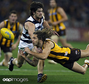 Hawthorns Chance Bateman handballs away from Geelongs Max Rooke during the AFL Round 17 match between the Hawthorn Hawks and the Geelong Cats at the MCG. GSP Images