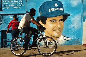 People pass by a painting of Brazilian F1 champion Ayrton Senna in Sao Paulo, Brazil, on Friday, April 30, 2004. Senna died following his fatal car crash at Imola track, Italy, on May 1, 1994. The writing in the wall reads "Every F1 driver has a limit. Mine is a little bit higher", in words supposedly spoken by Ayrton Senna. AP Photo/Alexandre Meneghini