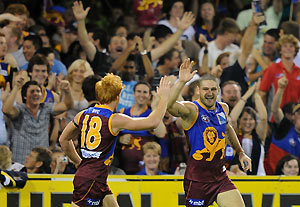 Lions player Brendan Fevola (r) reacts after kicking a spectacular grubber kick goal. AAP Image/Dave Hunt