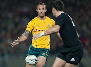 Australia's Quade Cooper kicks midfield in front of Daniel Carter during the Investec Tri Nations rugby