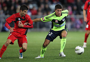 Adelaide United's Zenon Caravella tackles Melbourne Victory's Harry Kewell. AAP Image/James Elsby