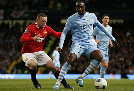 Manchester City's Yaya Toure competes for the ball with Manchester United's Wayne Rooney. AP Photo/Matt Dunham