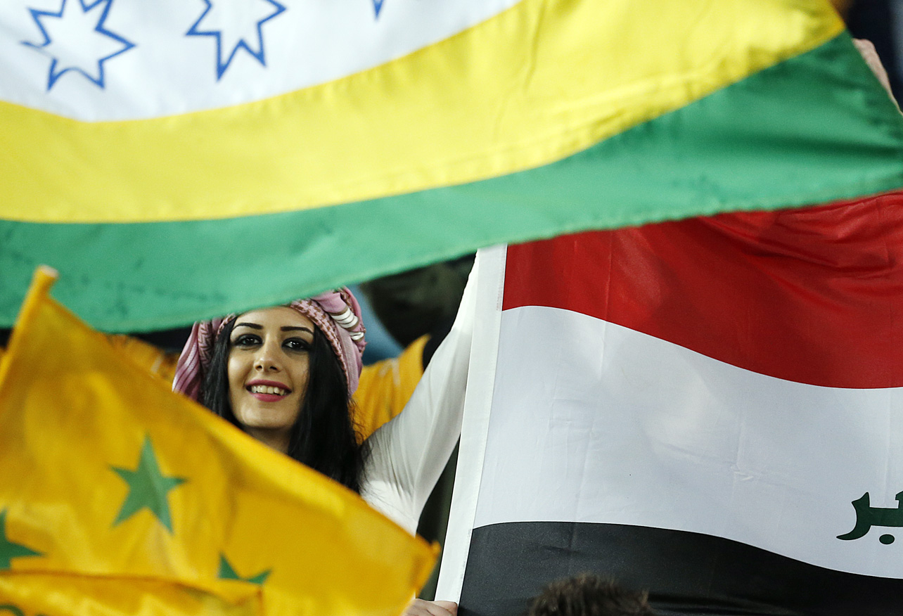 An Iraqui fan peers through flags before the start of the match at Stadium Australia. (Photo: Paul Barkley/LookPro)