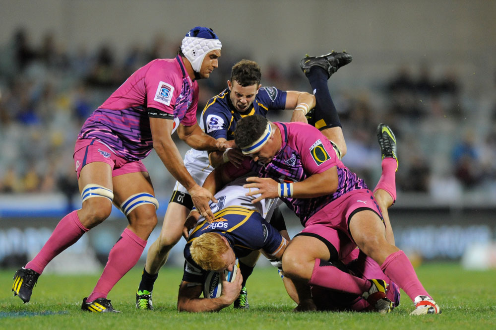 ACT Brumbies' Peter Kimlin (centre) is tackled by Bulls' Petrus Kruger. (AAP Image/Lukas Coch)