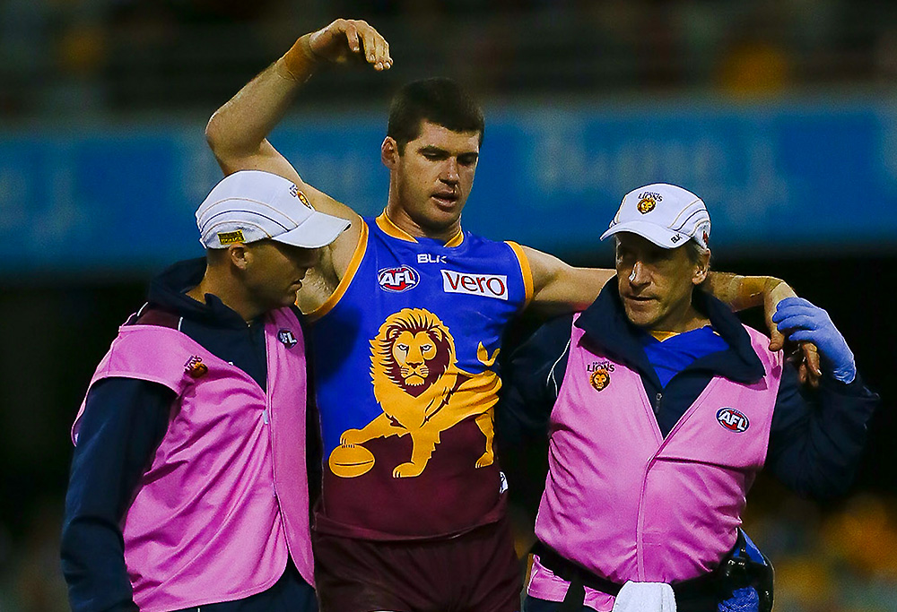 Brisbane Lions player Jonathan Brown is assisted from the field