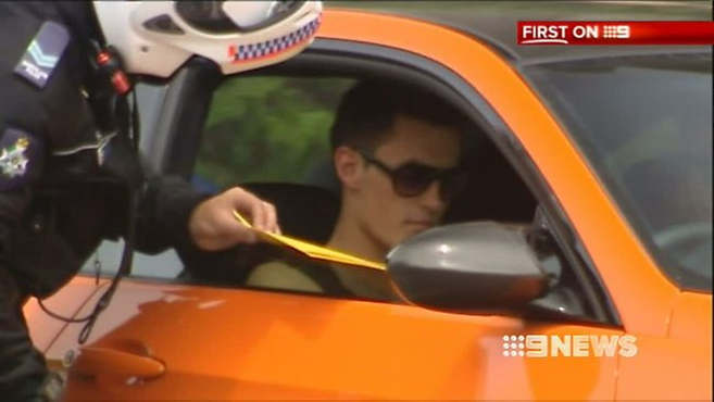 Bernard Tomic receiving one of several mock-tickets from Gold Coast police. (Image: Nine Network)