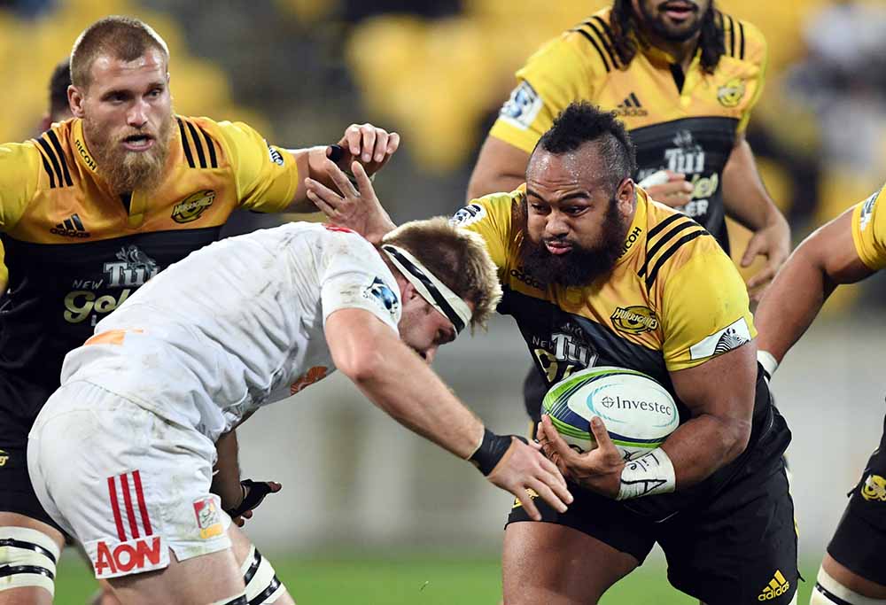 Loni Uhila of the Hurricanes, right, fends off Sam Cane of the Chiefs