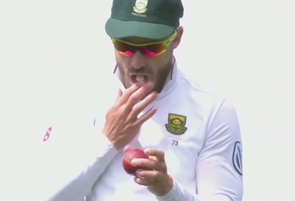 Faf du Plessis shines the ball with a mint in his mouth