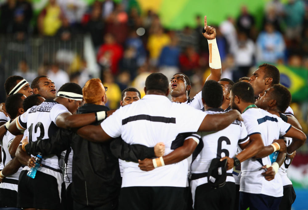 Fiji players and staff huddle as they win gold