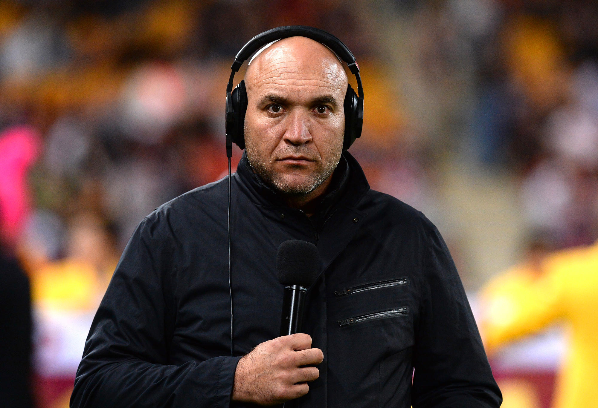 Gorden Tallis stands on the sidelines in commentary gear.