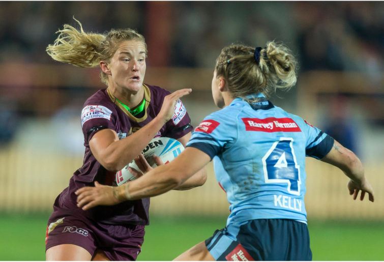 Meg Ward of the Maroons is tackled by Isabelle Kelly of the Blues.