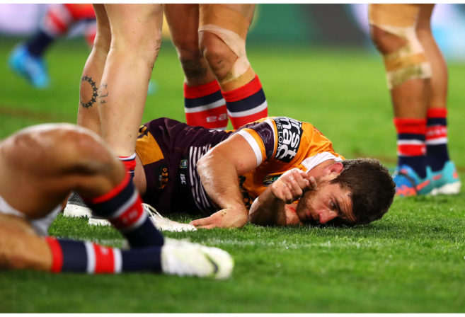 Andrew McCullough of the Broncos lies injured on the ground after a tackle by Dylan Napa.