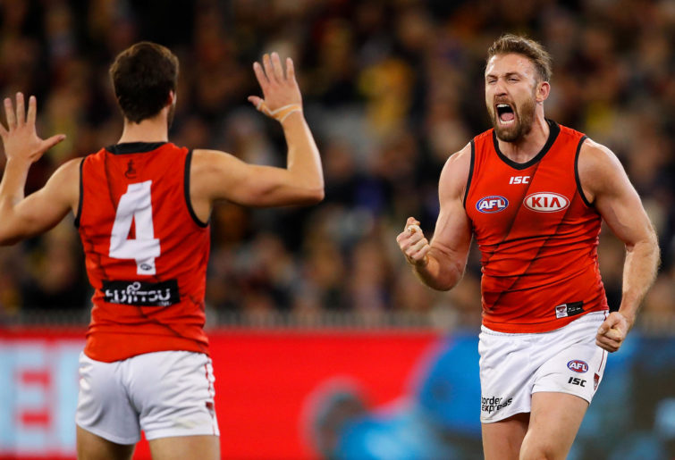 Cale Hooker of the Bombers (R) celebrates a goal with Kyle Langford of the Bombers during the 2018 AFL round 22 match between the Richmond Tigers and the Essendon Bombers at the Melbourne Cricket Ground on August 17, 2018 in Melbourne, Australia.