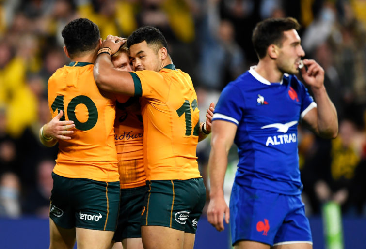 Tate McDermott of the Wallabies celebrates with his team mates Noah Lolesio and Hunter Paisami after scoring a try.