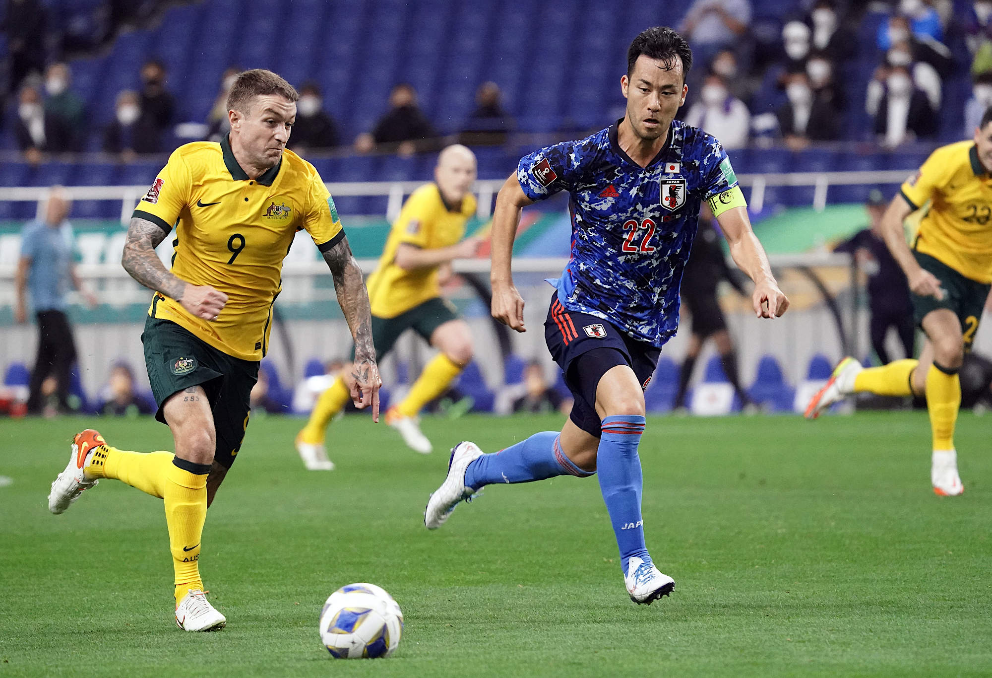 Adam Taggart of Australia controls the ball under pressure of Maya Yoshida of Japan