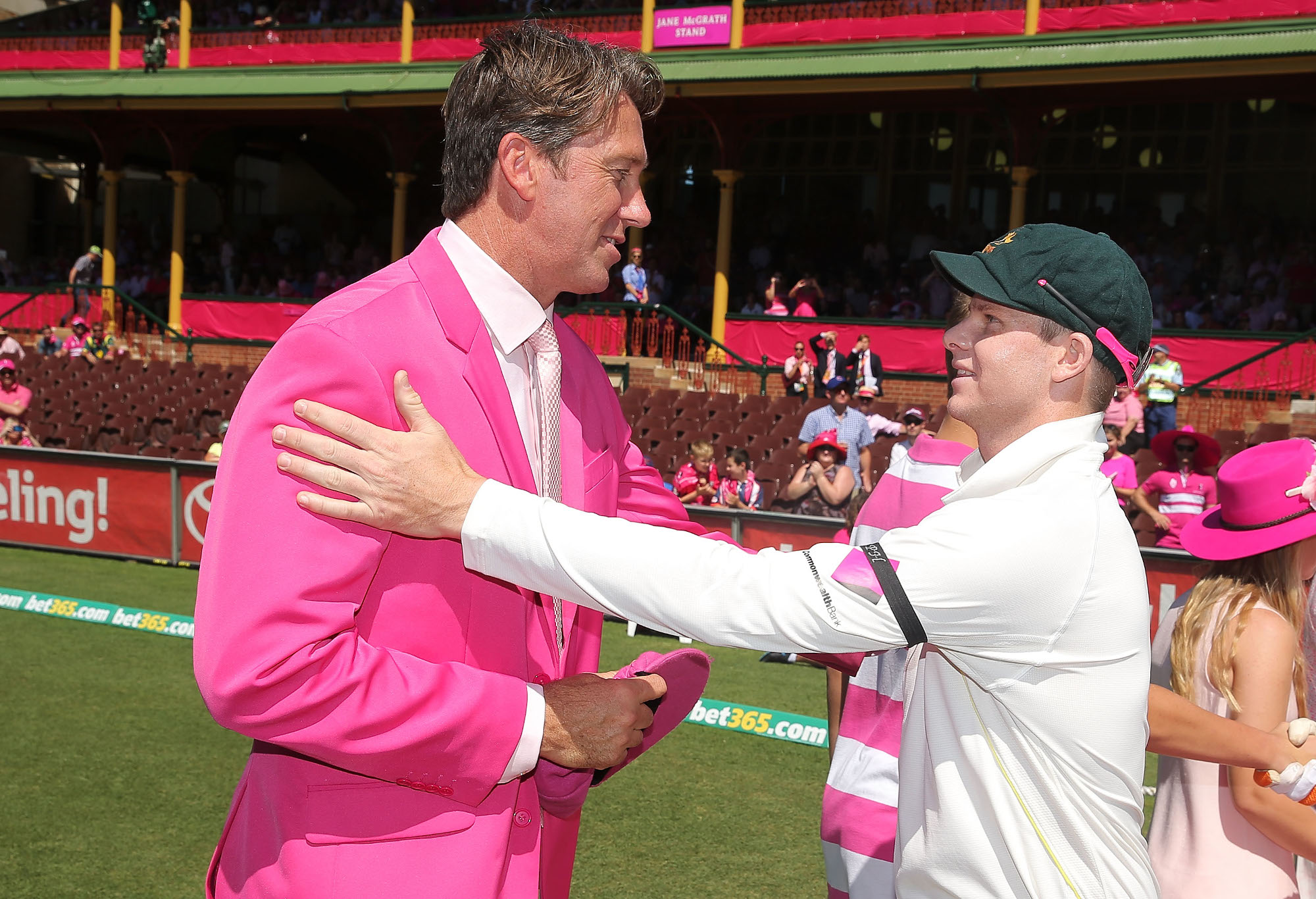 Glenn McGrath hands a pink cap to Steve Smith.