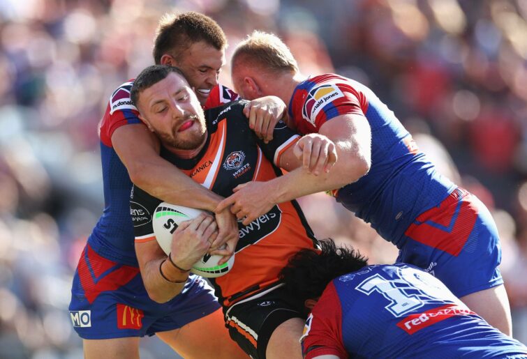 NEWCASTLE, AUSTRALIA - MARCH 20: Jackson Hastings of the Wests Tigers is tackled during the round two NRL match between the Newcastle Knights and the Wests Tigers at McDonald Jones Stadium, on March 20, 2022, in Newcastle, Australia. (Photo by Cameron Spencer/Getty Images)