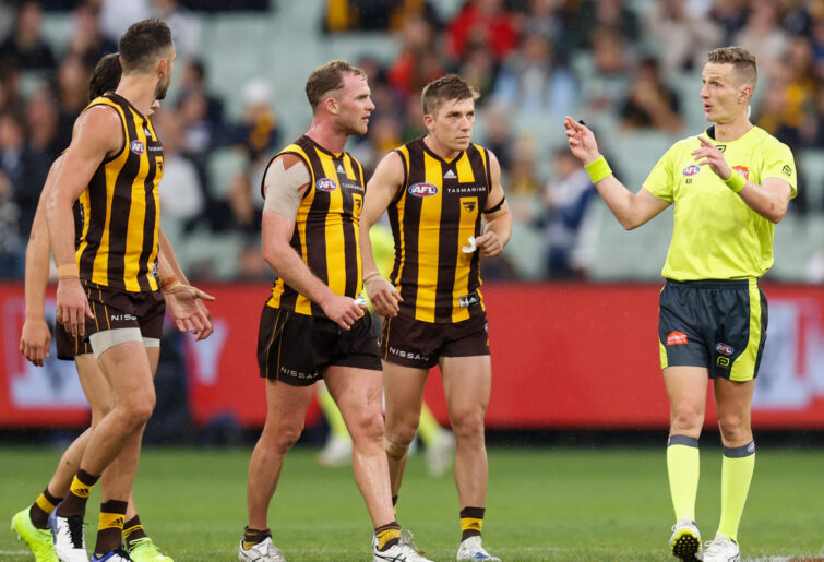 Tom Mitchell of the Hawks speaks with AFL umpire Hayden Gavine after a 50-metre penalty was awarded to Geelong.