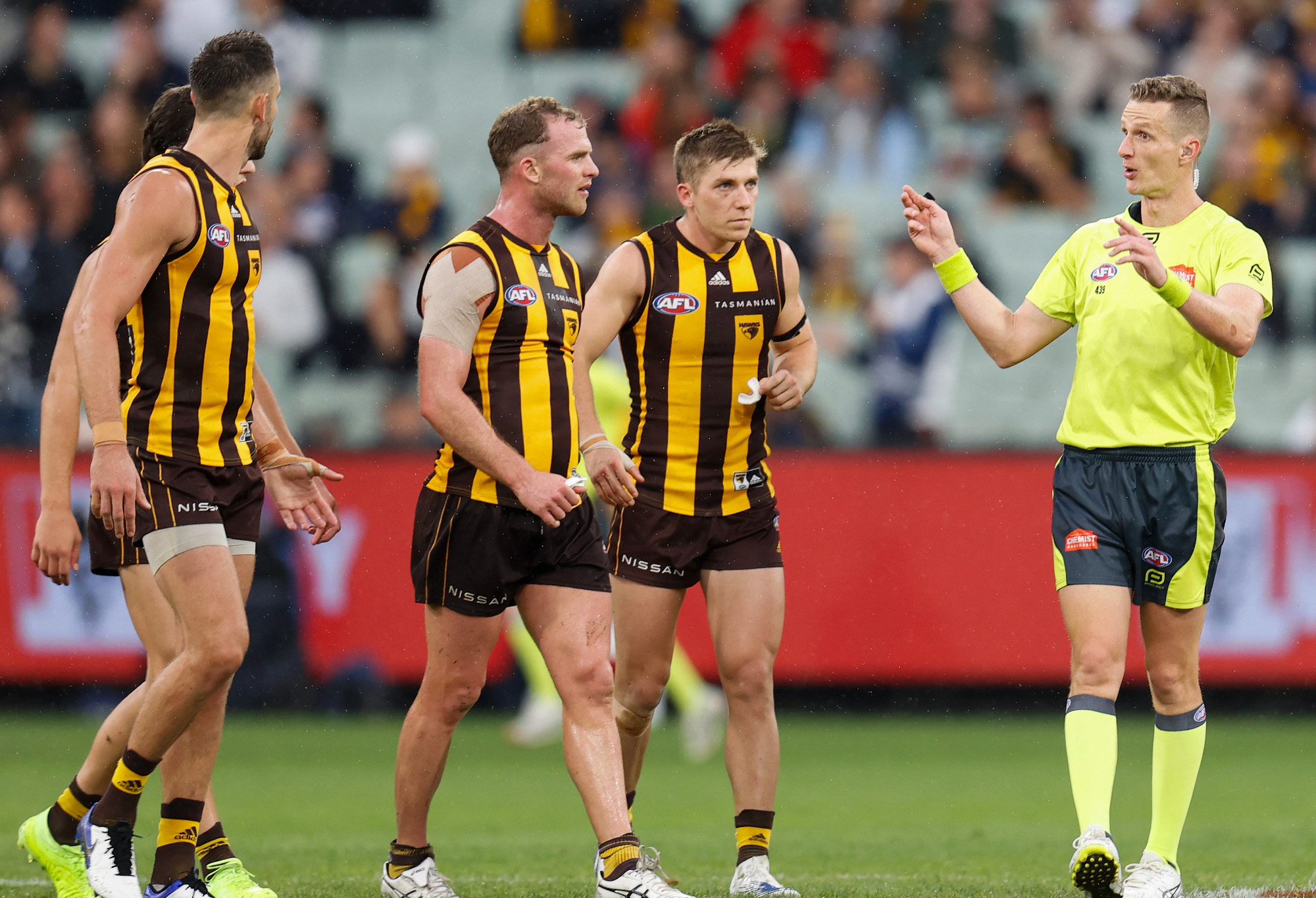 Tom Mitchell of the Hawks speaks with AFL umpire Hayden Gavine after a 50-metre penalty was awarded to Geelong.