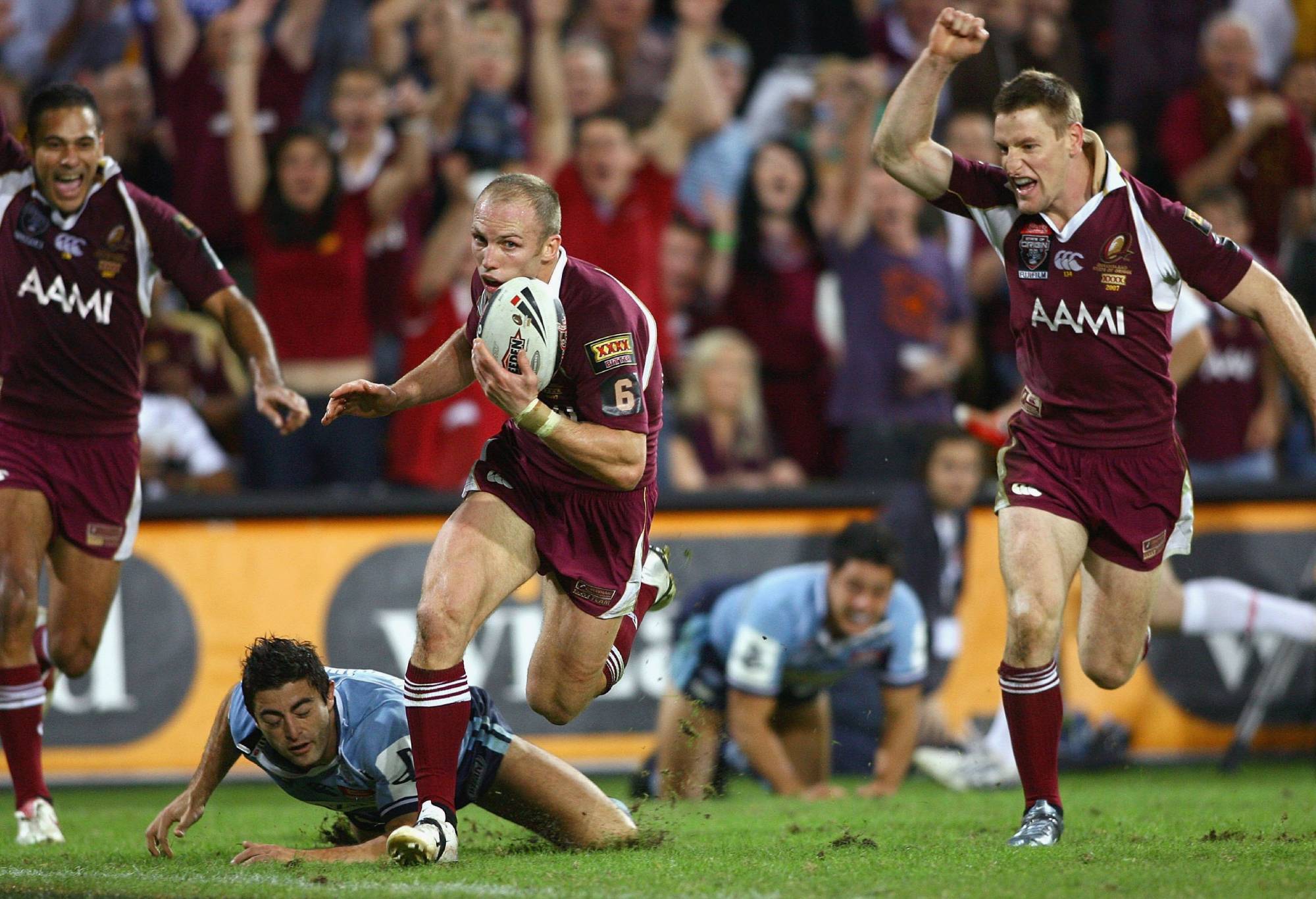 BRISBANE, AUSTRALIA - MAY 23: Darren Lockyer of the Maroons scores a try with team mates Justin Hodges (L) and Brent Tate (R) celebrating in the background during game one of the State of Origin series between the Queensland Maroons and the New South Wales Blues at Suncorp Stadium May 23, 2007 in Brisbane, Australia. (Photo by Bradley Kanaris/Getty Images)