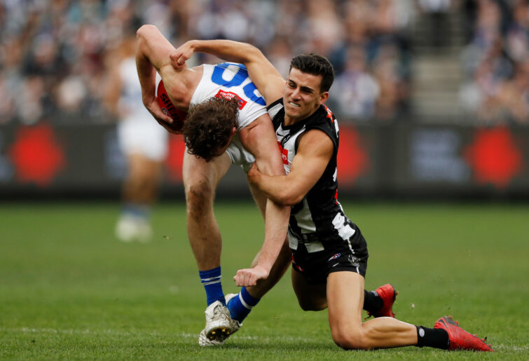 Nick Larkey of the Kangaroos is tackled by Nick Daicos of the Magpies.