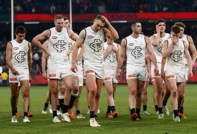 Dejected Carlton players walk from the ground after losing to Melbourne.