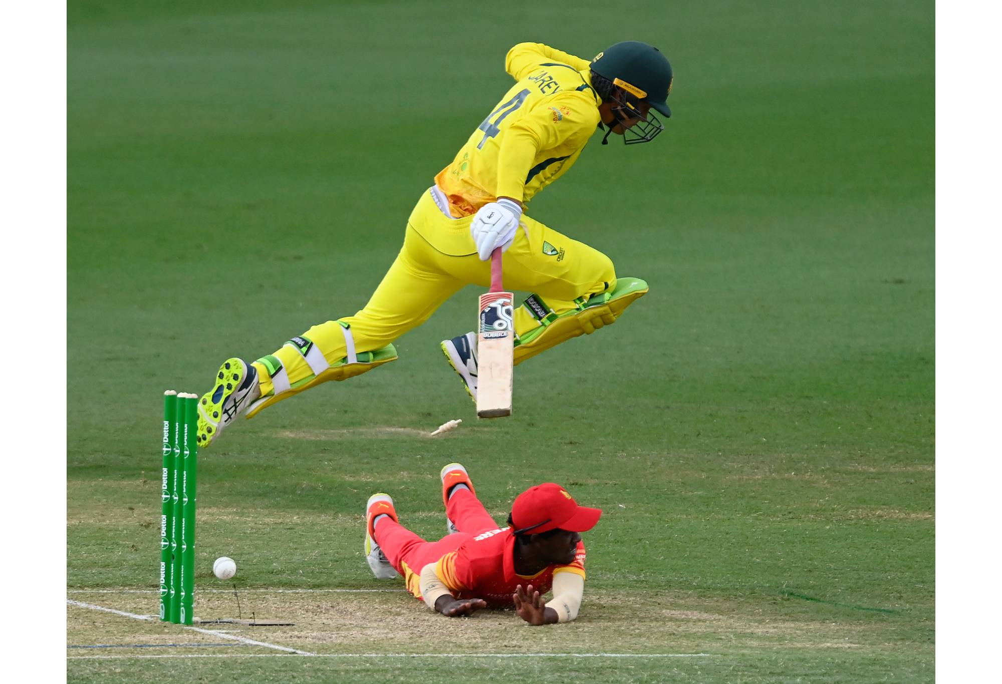 TOWNSVILLE, AUSTRALIA - AUGUST 31: Alex Carey of Australia jumps over Wessly Madhevere of Zimbabwe as he attempts a run out during game two of the One Day International series between Australia and Zimbabwe at Riverway Stadium on August 31, 2022 in Townsville, Australia. (Photo by Ian Hitchcock/Getty Images)