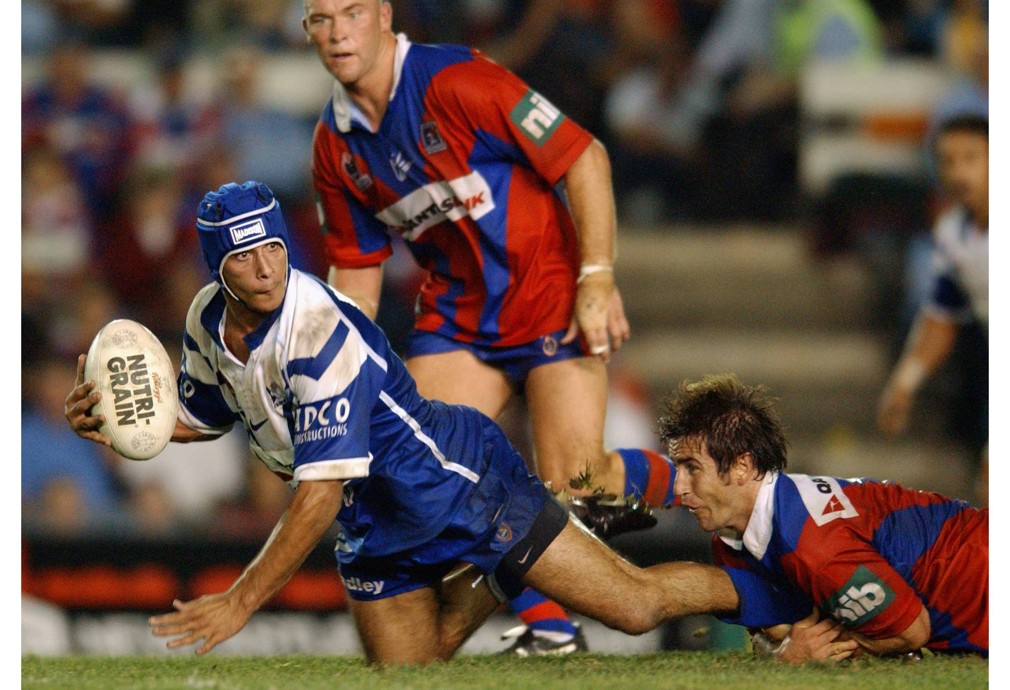 NEWCASTLE - APRIL 11:  Johnathan Thurston #6 of the Bulldogs is tackled by Andrew Johns #7 of the Knights during the round five NRL match between the Newcastle Knights and the Bulldogs held at Energy Australia Stadium in Newcastle, Australia on April 11, 2003. (Photo by Nick Laham/Getty Images)
