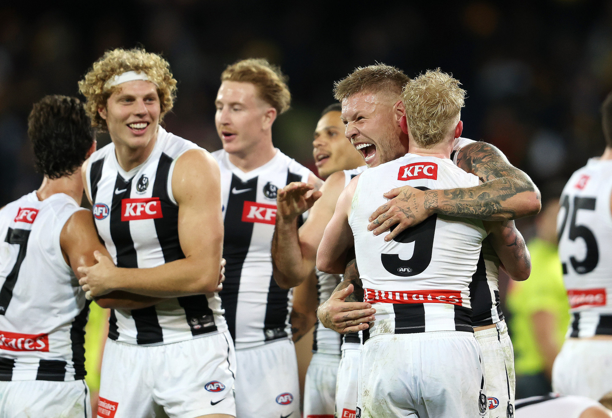 Jordan De Goey of the Magpies celebrates with John Noble and Collingwood teammates.