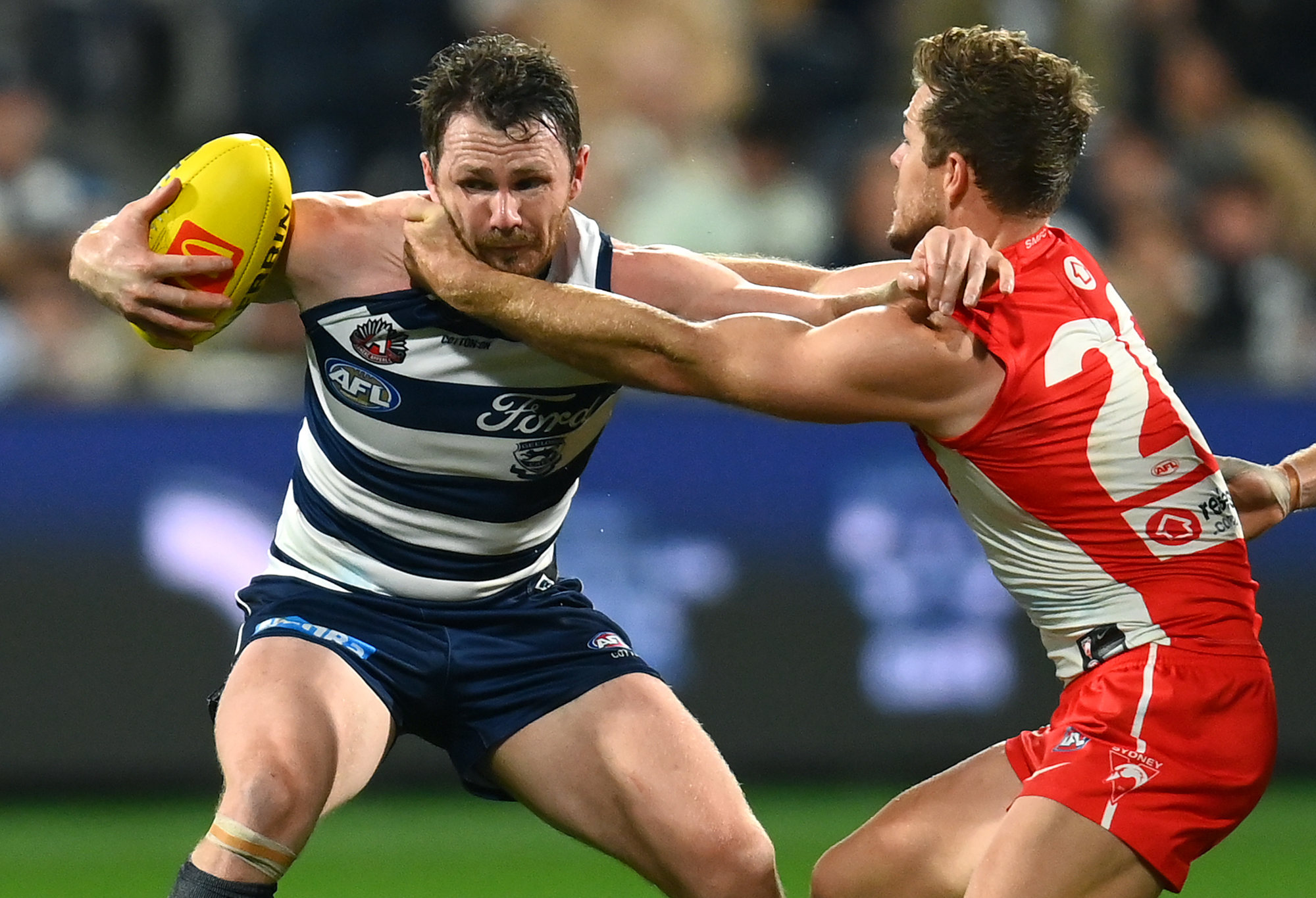 Patrick Dangerfield of the Cats is tackled by Luke Parker of the Swans.