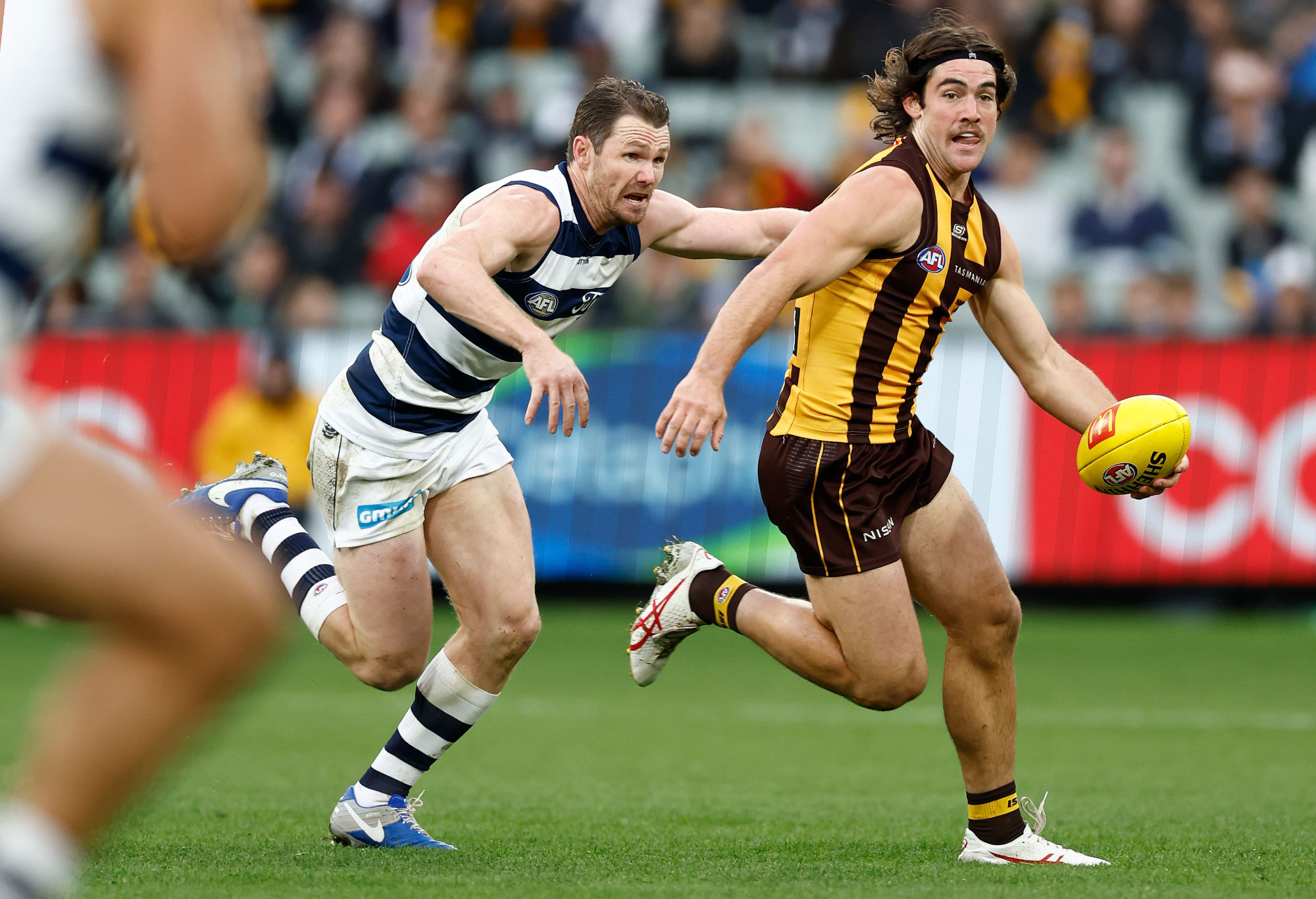Jai Newcombe of the Hawks is tackled by Patrick Dangerfield of the Cats.