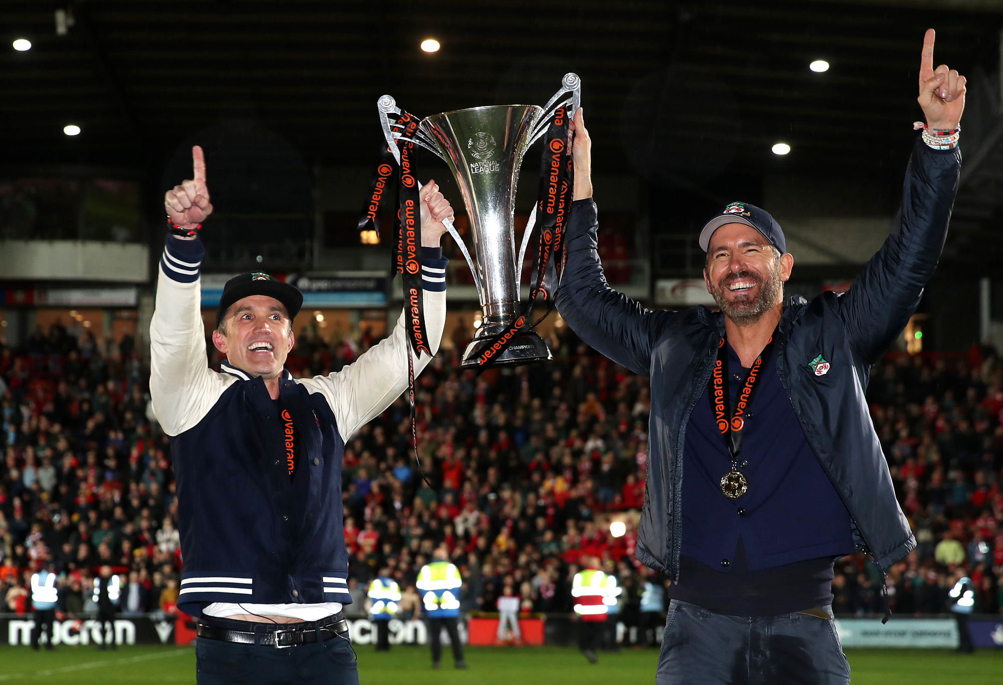 Rob McElhenney and Ryan Reynolds, owners of Wrexham, celebrate with the Vanarama National League trophy.