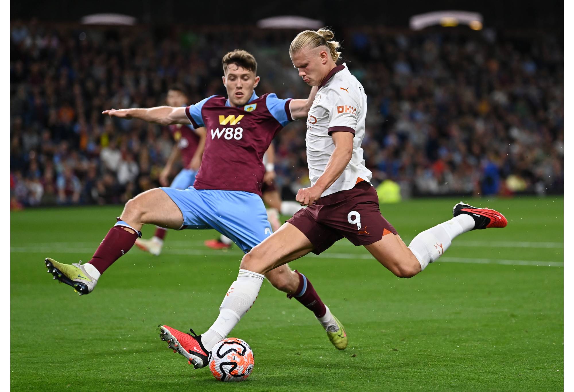 BURNLEY, ENGLAND - AUGUST 11: Erling Haaland of Manchester City crosses the ball whilst under pressure from Dara O'Shea of Burnley during the Premier League match between Burnley FC and Manchester City at Turf Moor on August 11, 2023 in Burnley, England. (Photo by Michael Regan/Getty Images)