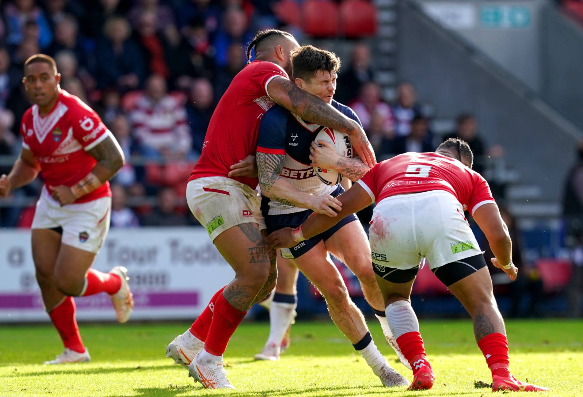 England's John Bateman is tackled by Tonga's Siliva Havili (right) and Addin Fonua-Blake during the International Test Series match at the Totally Wicked Stadium, St. Helens. Picture date: Sunday October 22, 2023. (Photo by Martin Rickett/PA Images via Getty Images)