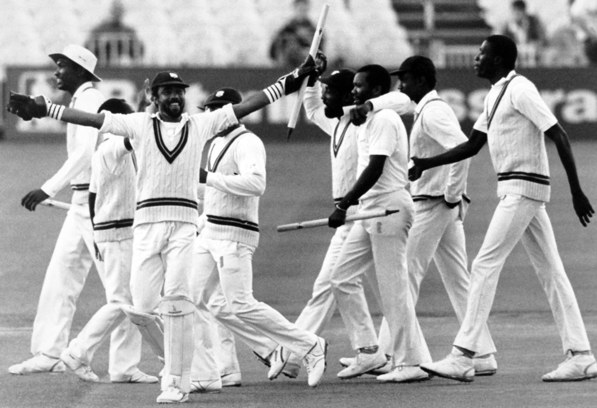 West Indies wicket-keeper Jeff Dujon (left) waves a stump at the crowd, whilst Viv Richards puts his arm around team mate Malcom Marshall as they celebrate with the rest of a victorious team (Photo by PA Images via Getty Images)