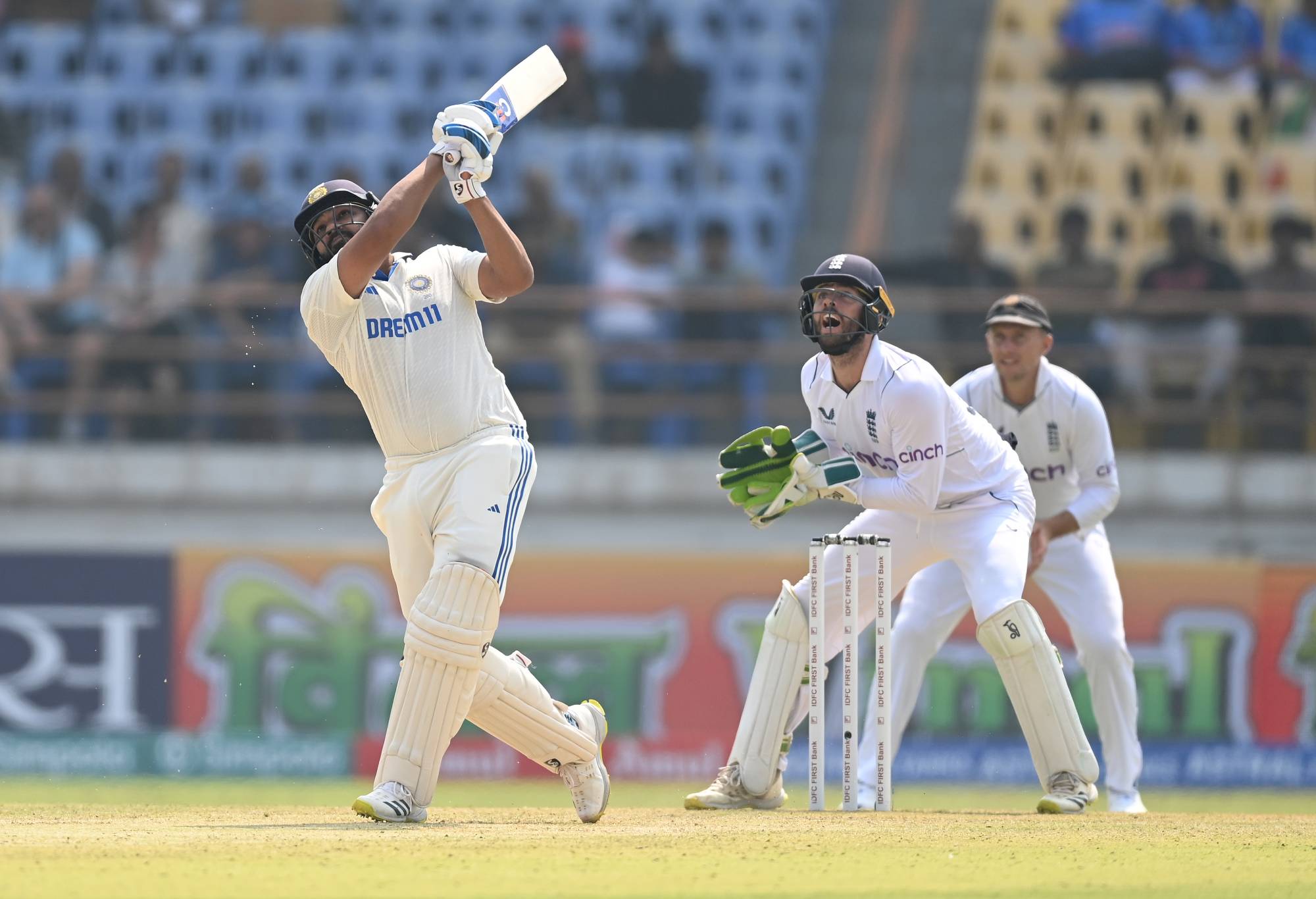 RAJKOT, INDIA - FEBRUARY 15: England wicketkeeper Ben Foakes looks on as India batsman Rohit Sharma hits out for six runs during day one of the 3rd Test Match between India and England at Saurashtra Cricket Association Stadium on February 15, 2024 in Rajkot, India. (Photo by Gareth Copley/Getty Images)