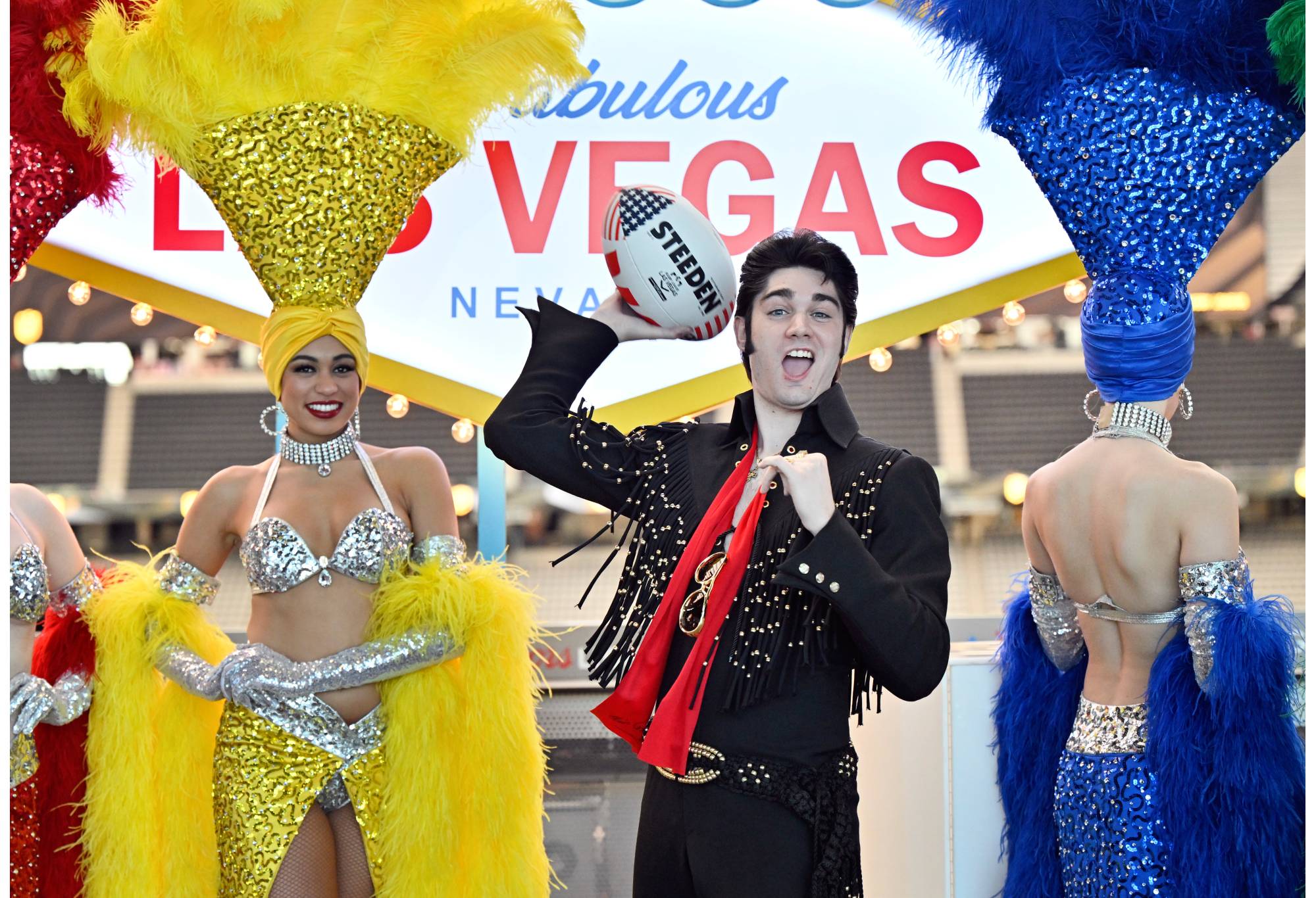 An Elvis impersonator wields a Steeden with Las Vegas showgirls. (Photo by David Becker/Getty Images for NRL)