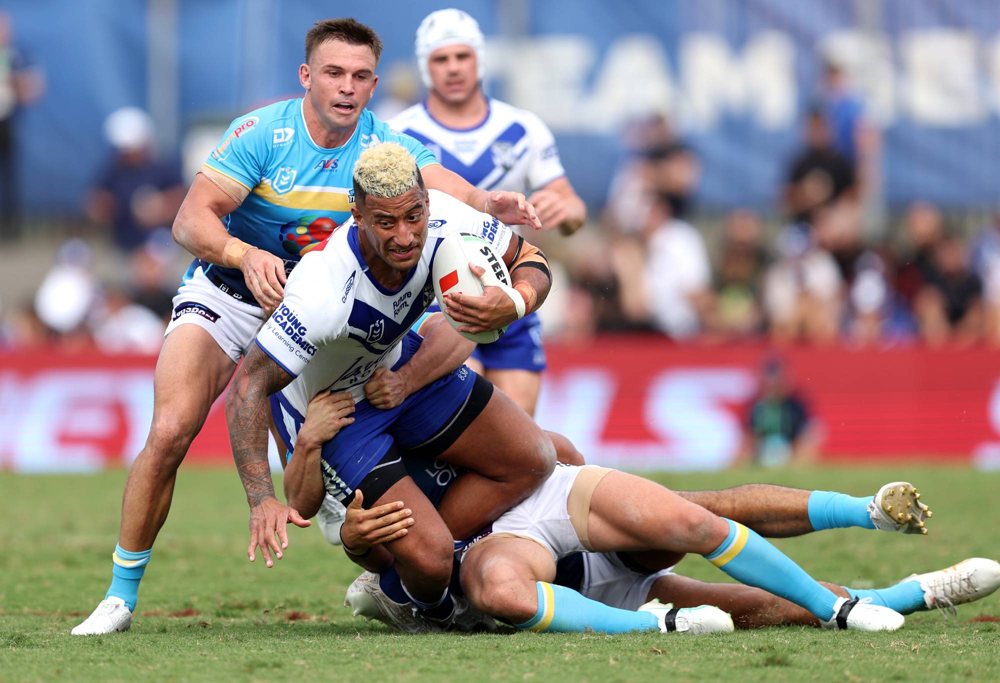 SYDNEY, AUSTRALIA - MARCH 23: Viliame Kikau of the Bulldogs is tackled by the Titans defence during the round three NRL match between Canterbury Bulldogs and Gold Coast Titans at Belmore Sports Ground, on March 23, 2024, in Sydney, Australia.